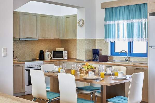 Une cuisine moderne avec des meubles en bois, un four à micro-ondes, une cuisinière et un coin repas avec une table mise pour le petit-déjeuner.