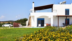 A modern two-story house with a swimming pool, a car parked outside, and a garden with yellow flowers. - Nerida Beachfront Villas (Rhodes)