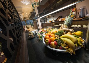 Een presentatie van fruit met verschillende soorten fruit en een koffieapparaat in een moderne omgeving.