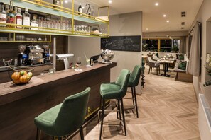 A bar area with stools, a counter, and a shelf with bottles.