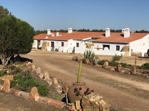 A white building with red-tiled roofs and stone chimneys.