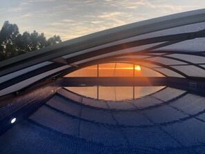 A swimming pool with a glass ceiling and a sunset view. - Quinta das Beldroegas - Casas de Campo (Odemira)