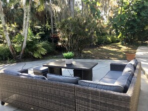 Un área de estar al aire libre con muebles de mimbre y una mesa central.
