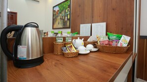 A reception area with a coffee maker, baskets of snacks, and a painting on the wall.