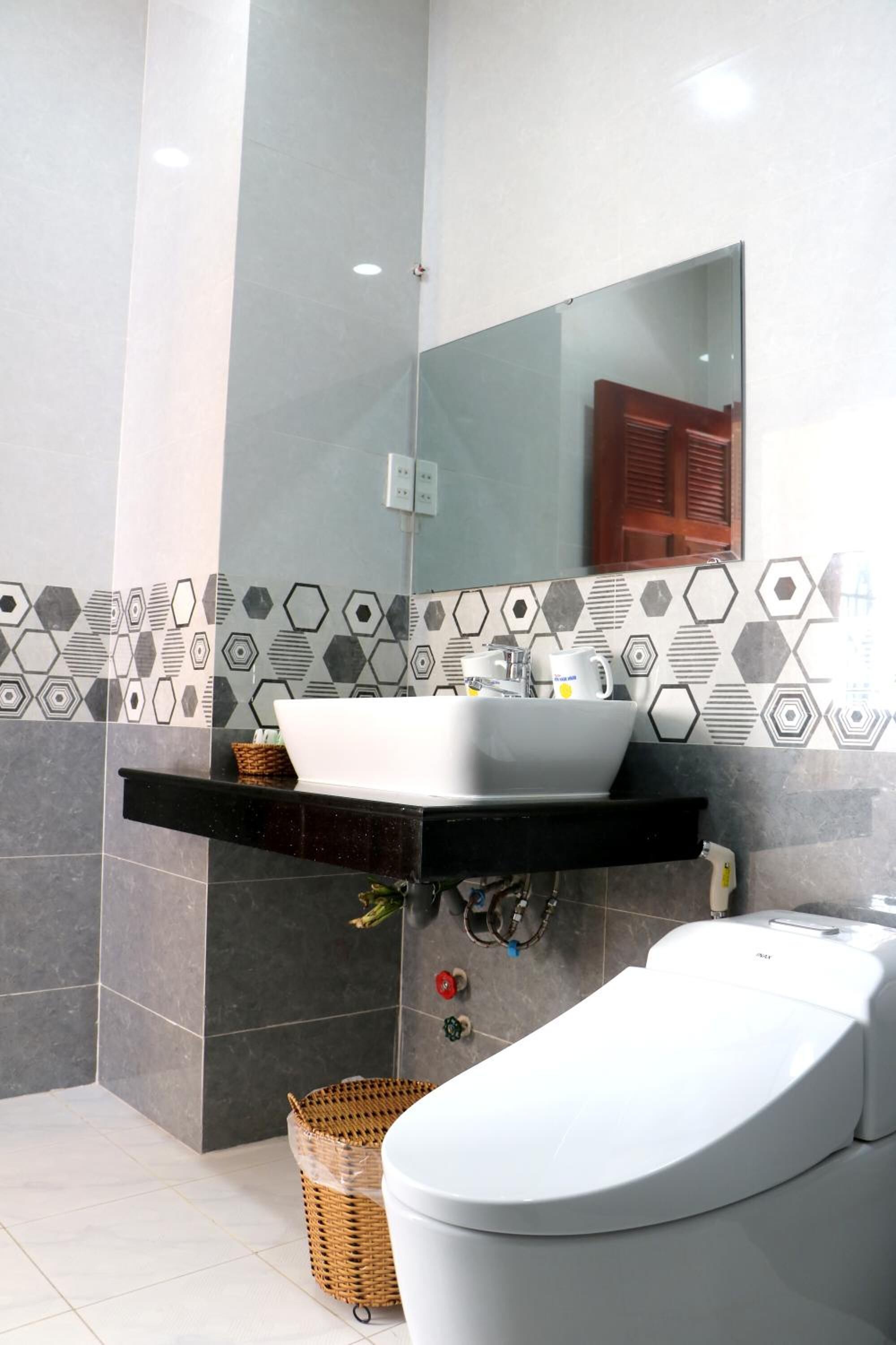 Un bagno moderno con un lavandino bianco, uno specchio grande e un water bianco.