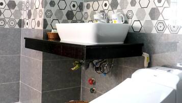 Un bagno moderno con un lavandino bianco, uno specchio grande e un water bianco.