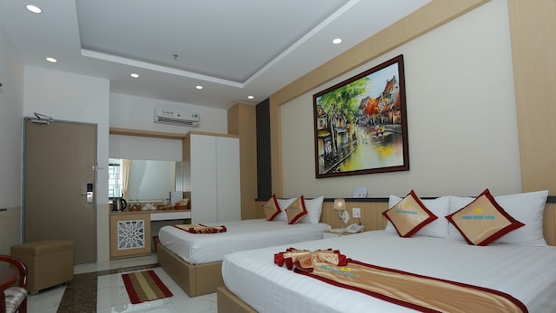 A hotel room with two beds, a desk, a mirror, and a painting on the wall.