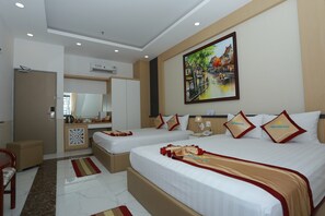 A hotel room with two beds, a desk, a mirror, and a painting on the wall. - Minh Minh Nam Hotel (Can Tho)