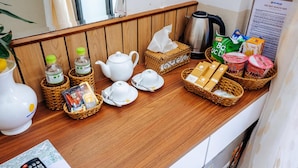 A breakfast setup with tea, coffee, and snacks on a wooden counter.