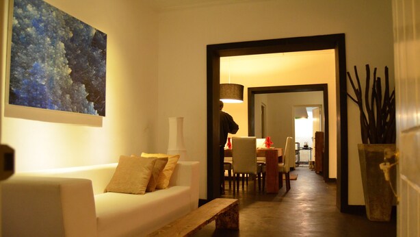 A modern living room with a white sofa, a wooden bench, and a painting on the wall. - Loversleap Cottage (Nuwara Eliya)
