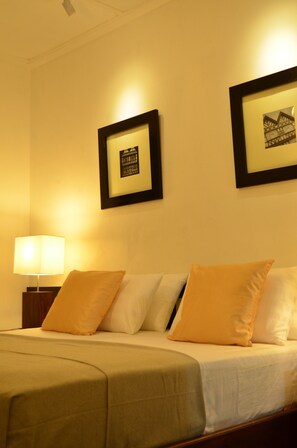 A hotel room with a bed, a nightstand with a lamp, and two framed pictures on the wall.
