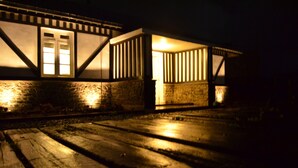 A building with a stone facade and wooden beams, illuminated by warm interior lighting. - Loversleap Cottage (Nuwara Eliya)
