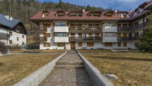 A multi-story hotel with balconies, a central courtyard, and a mountainous backdrop. - GuestHost - Modern APT just 2 steps from the Ciclovia! x3 (Tarvisio)