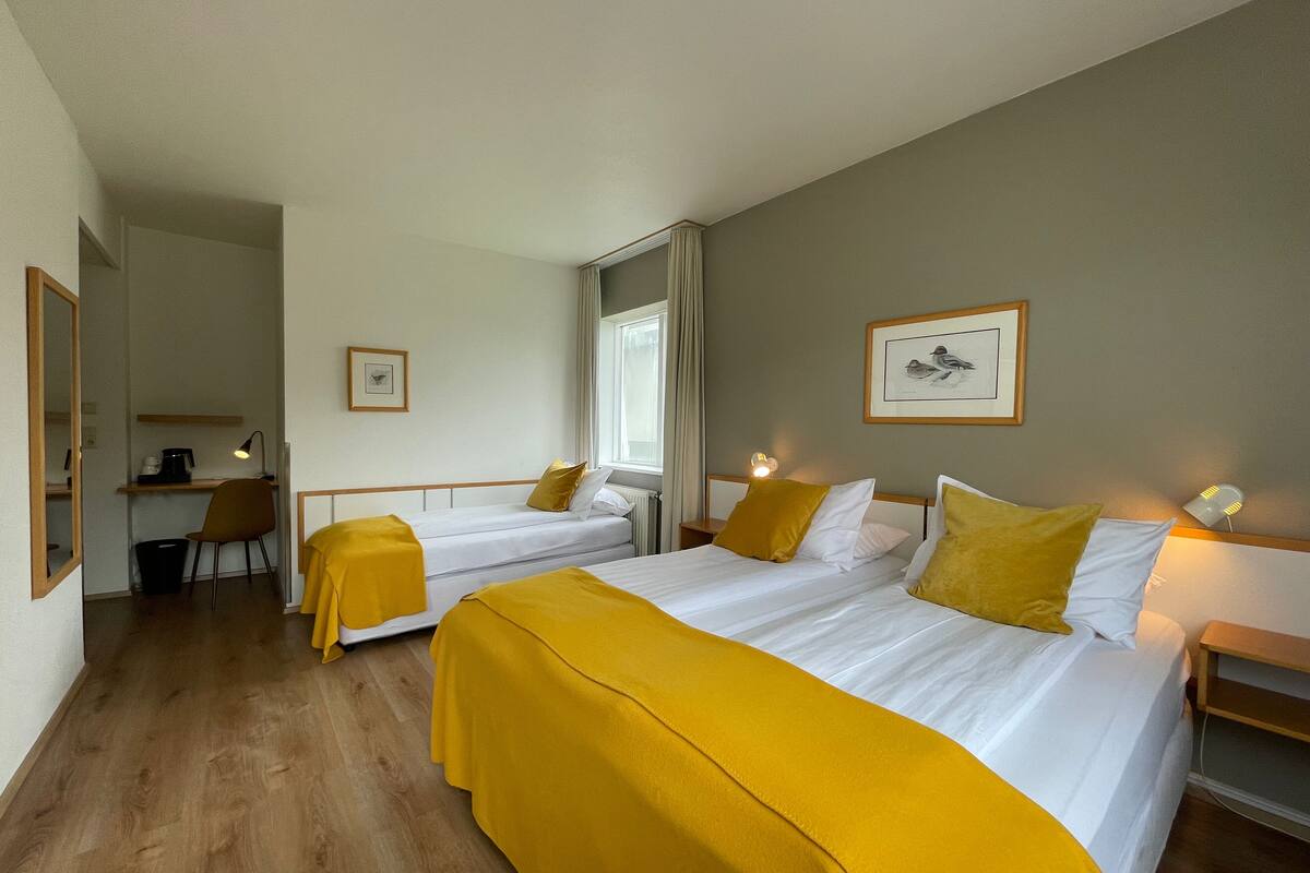 Ein Hotelzimmer mit zwei Betten, einem Schreibtisch und einem Stuhl.