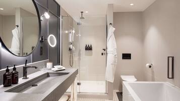 A modern bathroom with a large mirror, a sink, a shower, and a bathtub.