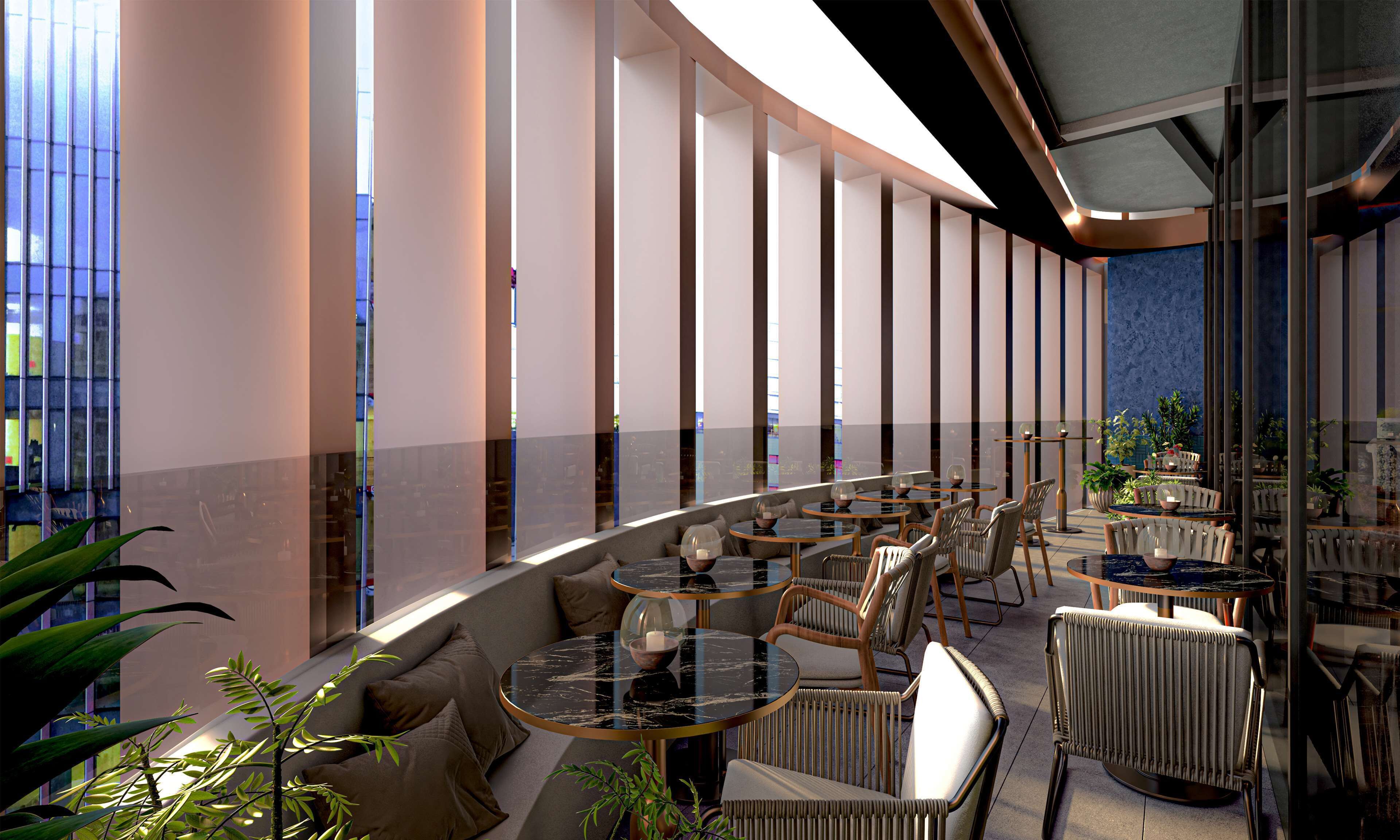 A modern indoor dining area with round tables and cushioned seating, large windows, and indoor plants.