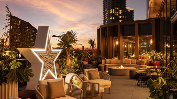 Un lounge en la azotea con asientos al aire libre, una gran decoración de estrella iluminada y vistas de la ciudad.