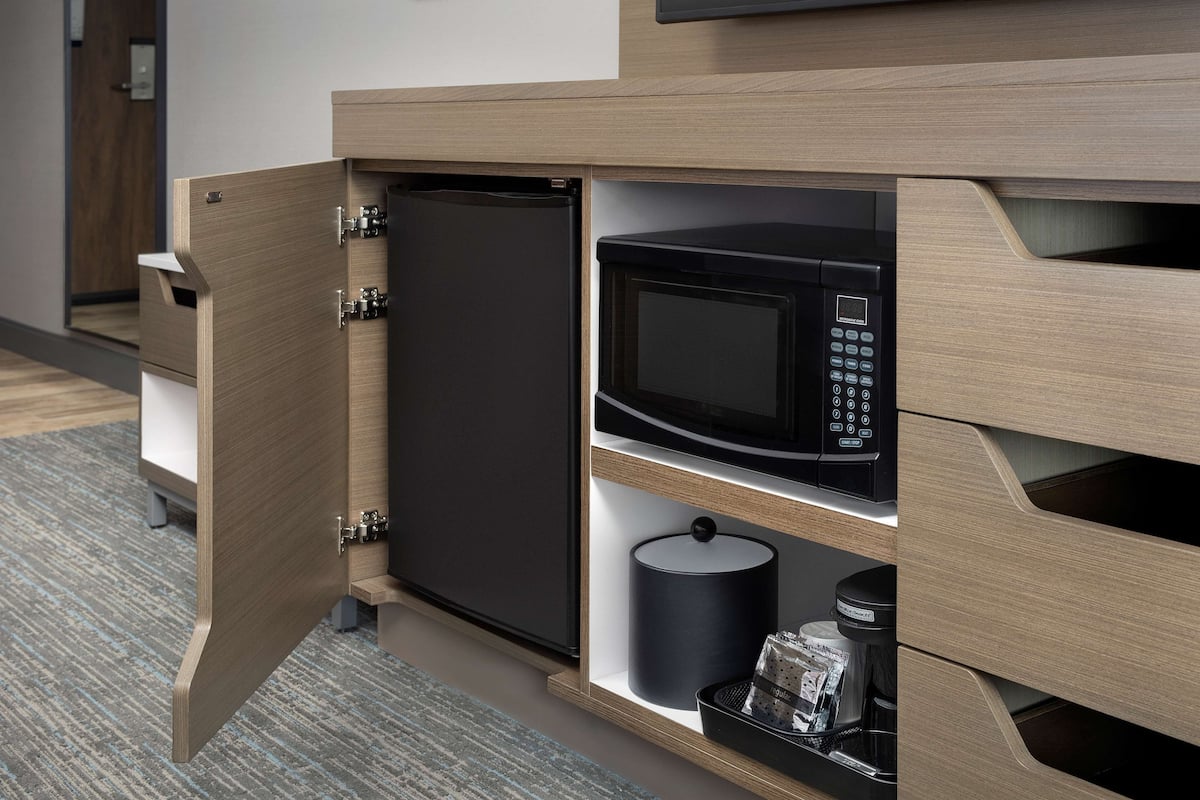 A compact kitchen area with a microwave, a small refrigerator, and a coffee maker.