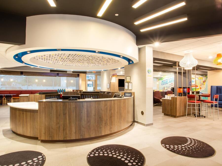 Een moderne hotellobby met een gebogen receptiebalie, een zithoek en een groot raam met uitzicht op buiten.