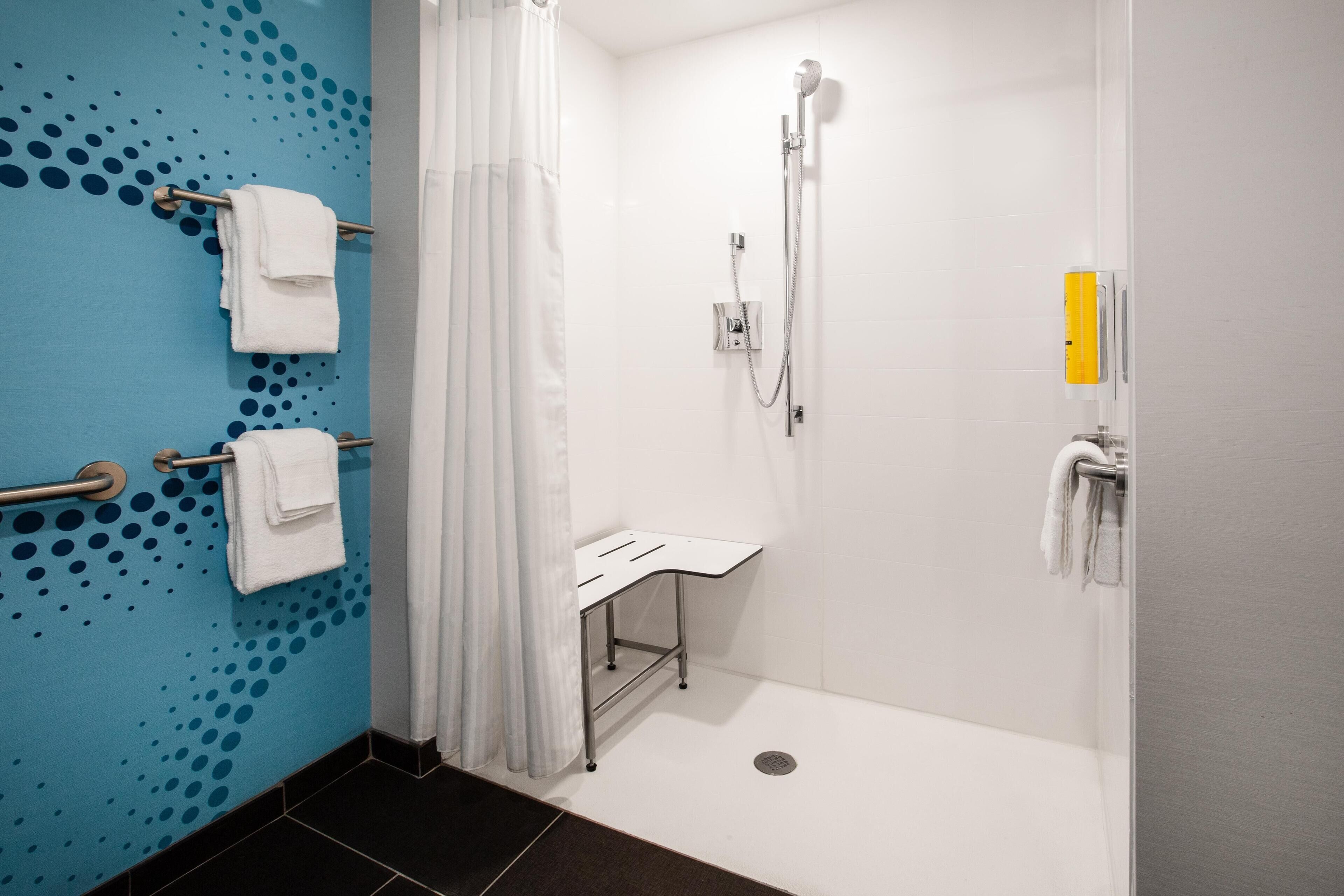 A modern bathroom with a shower, a sink, and a towel rack.