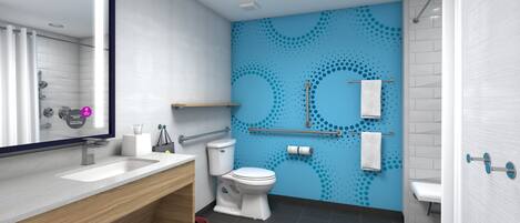 Un baño moderno con lavamanos, inodoro y zona de ducha blancos. Hay barras de apoyo y un perchero en la pared.