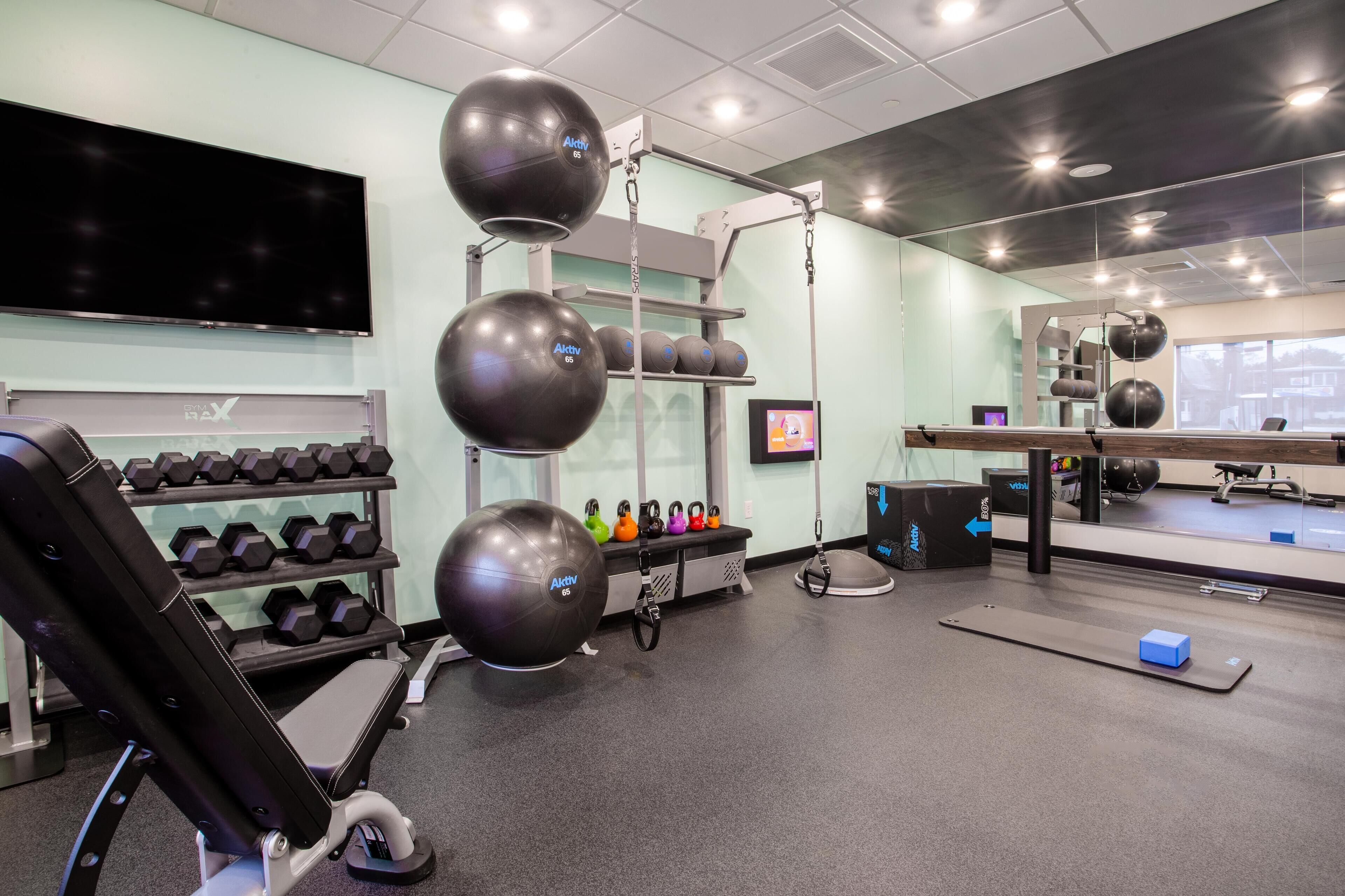 A gym with exercise equipment, a TV, and a mirror.