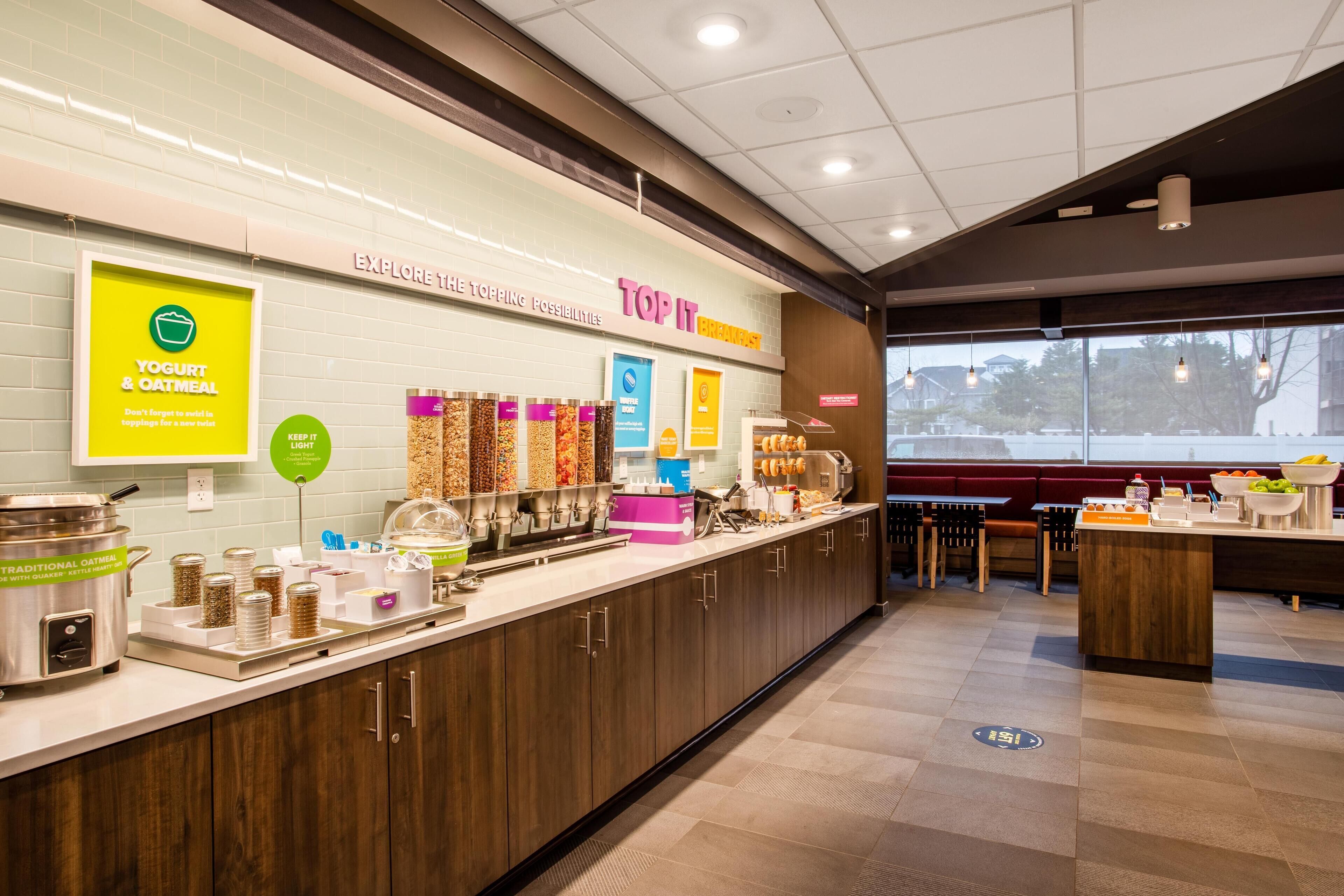 A breakfast bar with yogurt and oatmeal options, a variety of cereals, and a coffee station.
