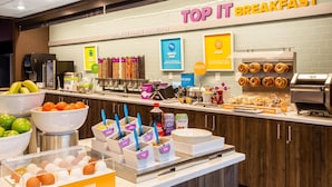 A breakfast buffet with various food options and a sign reading "TOP IT BREAKFAST".