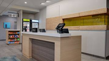 Zona de recepción de un hotel con mostrador, máquina expendedora y minibar.