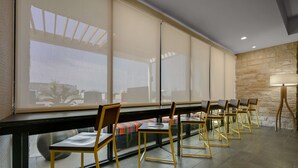 A conference room with a long table and chairs, large windows, and a stone wall. - Home2 Suites by Hilton Temple Medical Center (Temple)