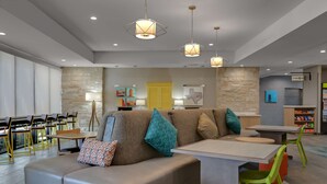 A modern interior with a seating area, tables, and a children's play area. - Home2 Suites by Hilton Temple Medical Center (Temple)
