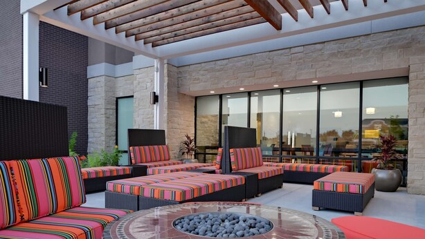 A modern outdoor seating area with cushioned sofas and a central fire pit. - Home2 Suites by Hilton Temple Medical Center (Temple)