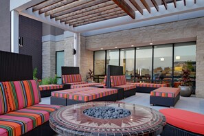 A modern outdoor seating area with cushioned sofas and a central fire pit. - Home2 Suites by Hilton Temple Medical Center (Temple)