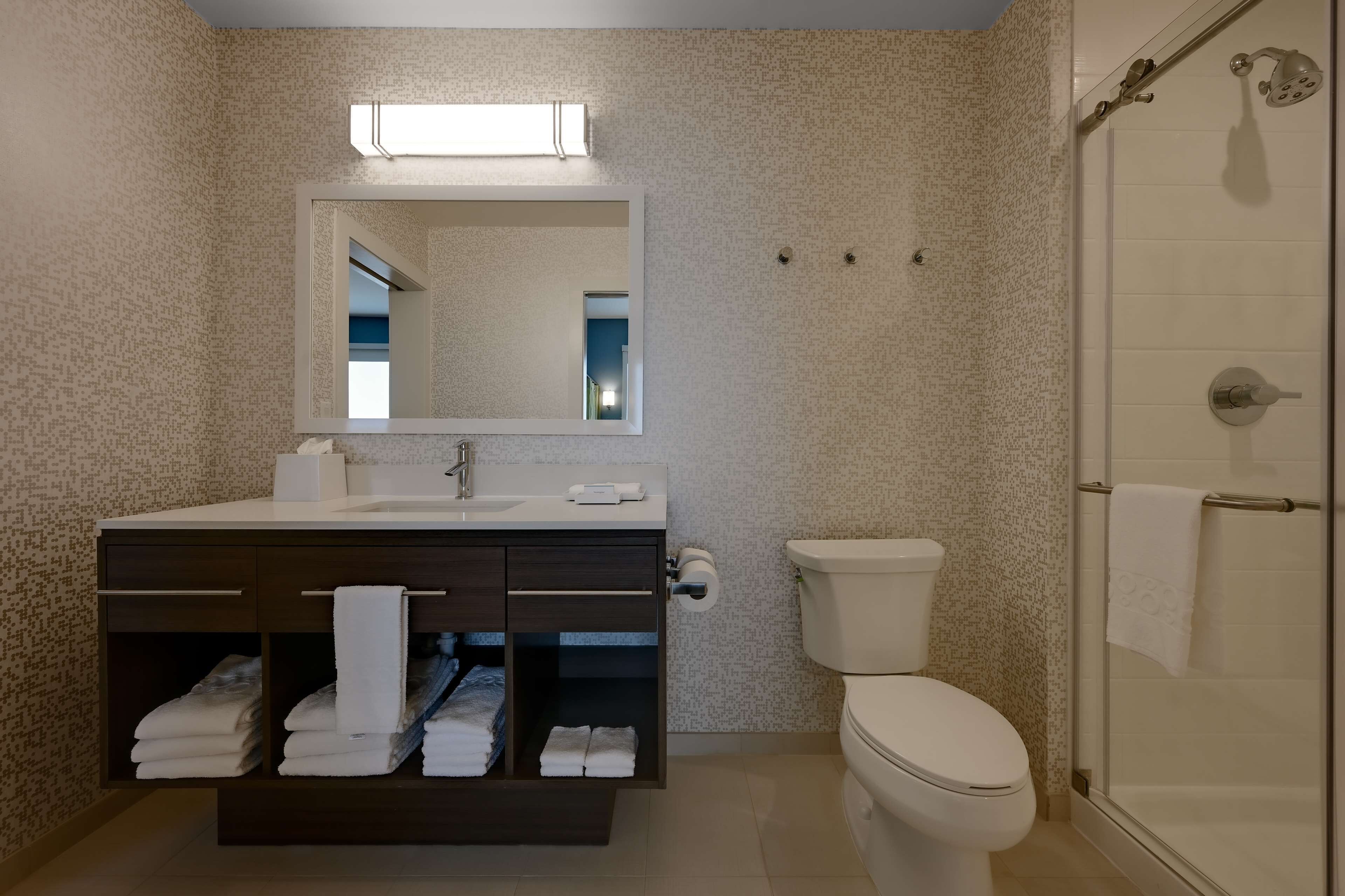 A modern bathroom with a large mirror, a toilet, and a shower.