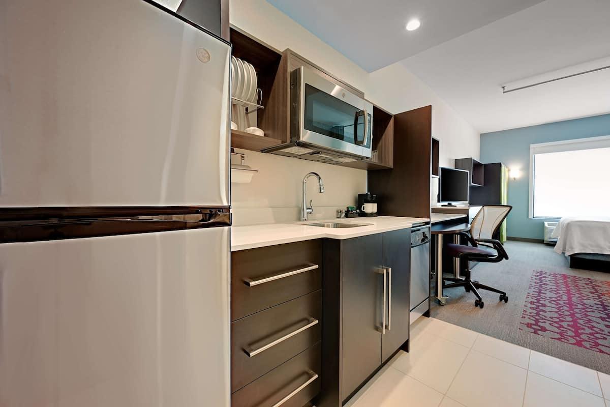 Una cocina moderna con electrodomésticos de acero inoxidable, microondas integrado y un lavamanos.