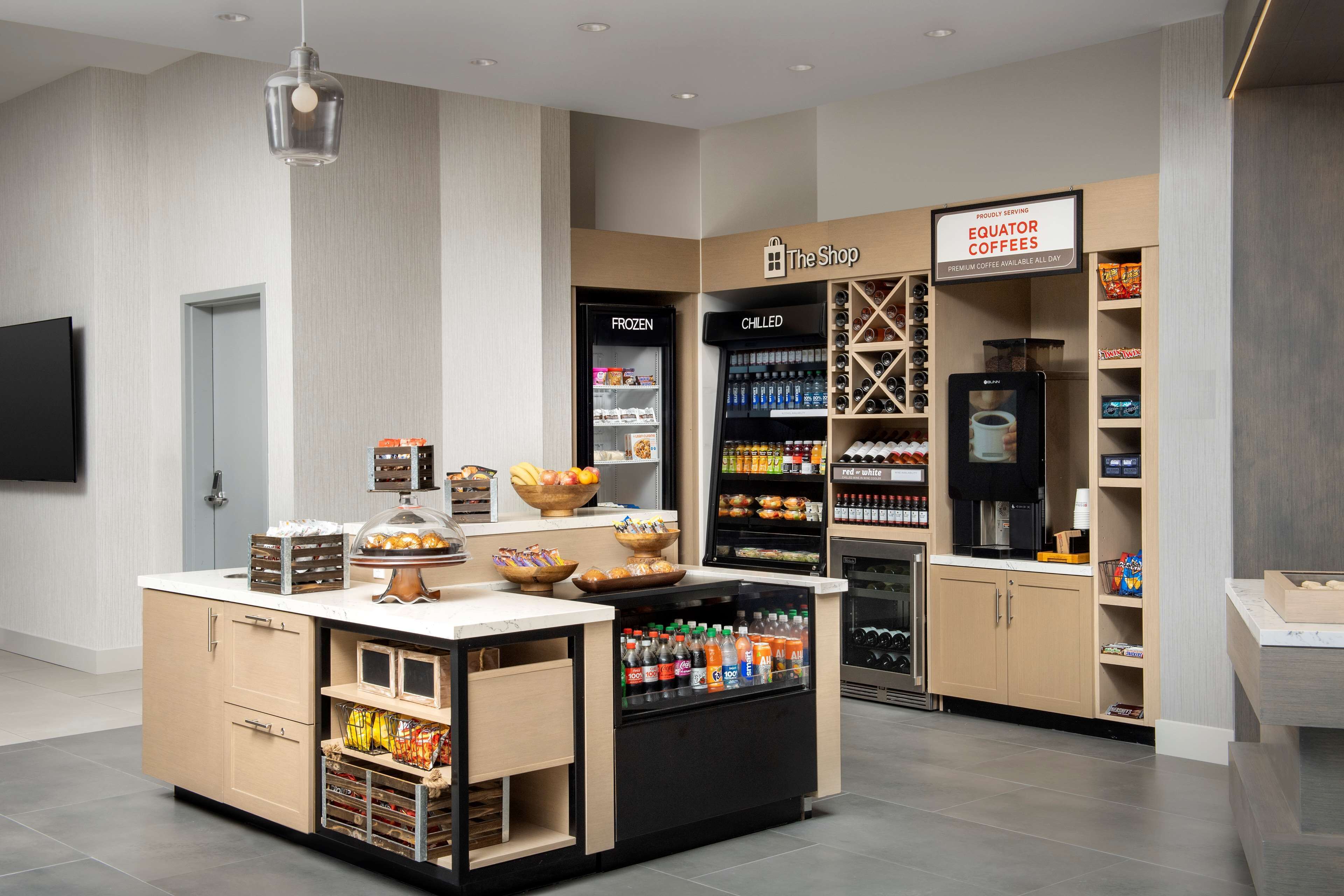 A modern coffee shop with a self-serve station, refrigerated and chilled beverage sections, and a variety of snacks.