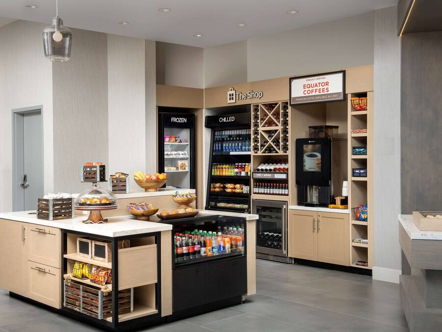 A modern coffee shop with a self-serve station, refrigerated and chilled beverage sections, and a variety of snacks.