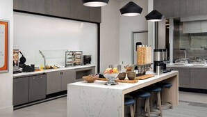 A modern kitchen with a marble island, bar stools, and various appliances.