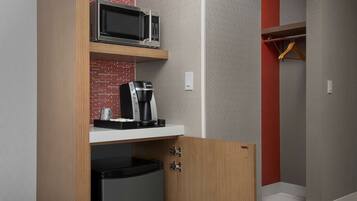 Una kitchenette compacta equipada con microondas, cafetera y refrigerador.