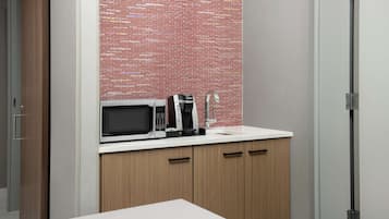 A kitchenette with a microwave, coffee maker, and a sink.