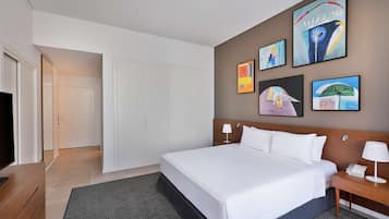 Habitación de hotel moderna con una cama grande, un televisor de pantalla plana, una mesita de noche de madera y obras de arte en las paredes.