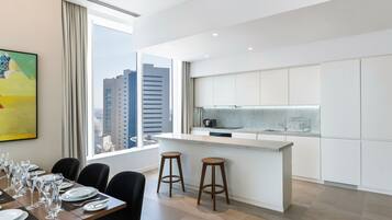 Una cocina moderna con una isla central, taburetes de bar y un comedor con una mesa dispuesta para seis personas.