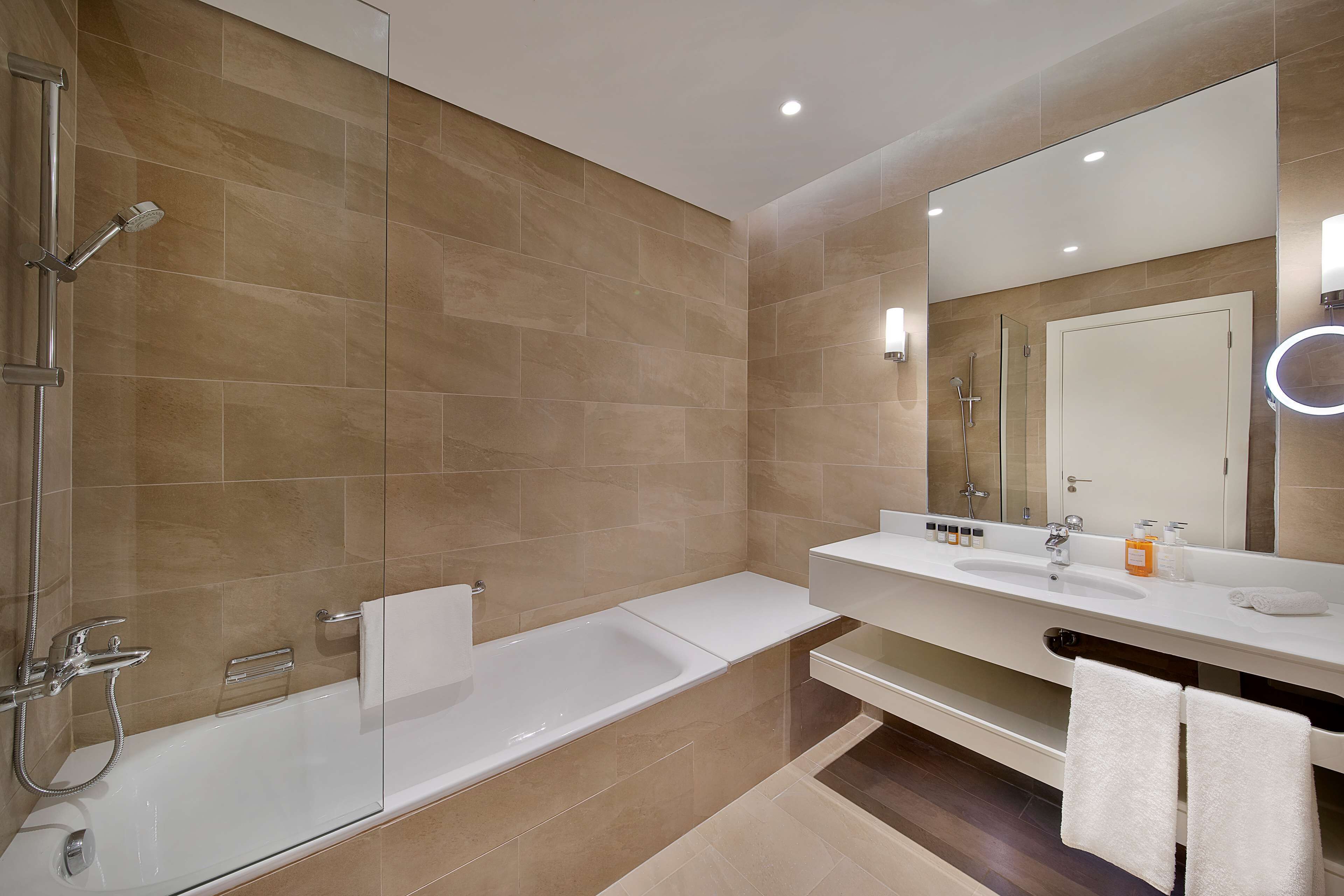 Un baño moderno con bañera, ducha y tocador con espejo.
