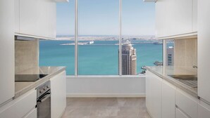 Una cocina moderna con amplios ventanales que ofrecen vistas a un paisaje urbano costero y al mar.