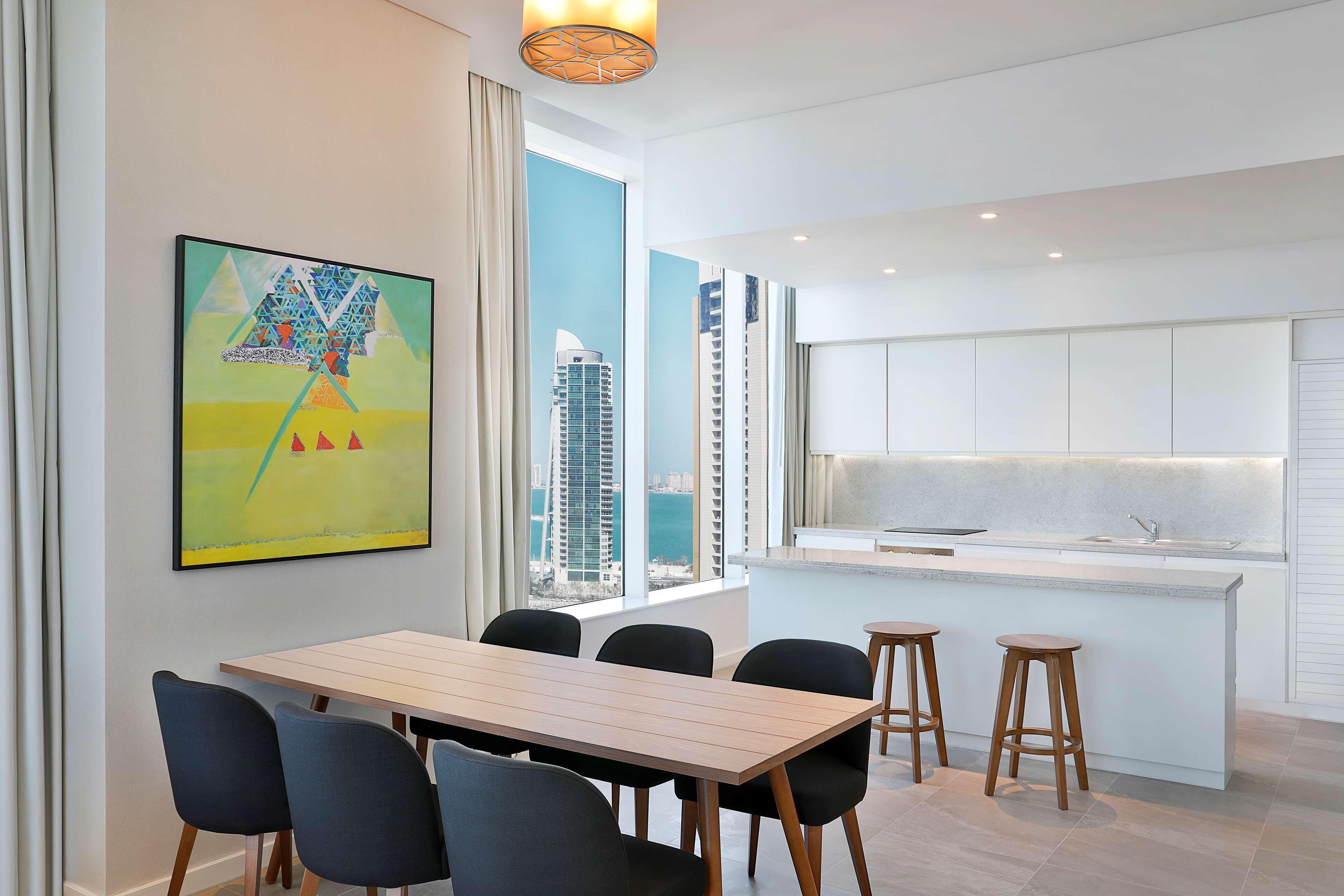 Een modern interieur met een eethoek, keuken en grote ramen met uitzicht op de stad.