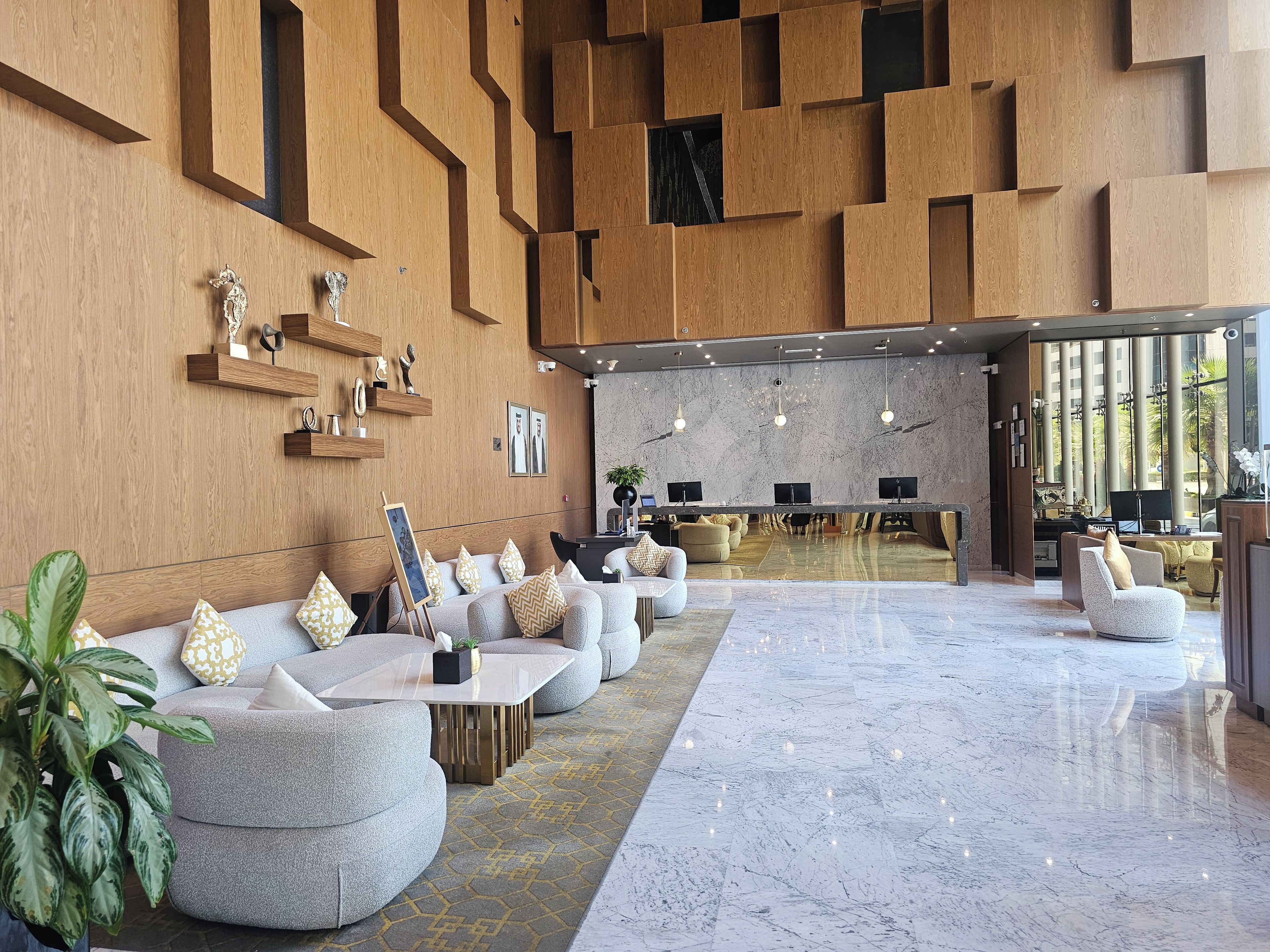 A modern lobby with a reception desk, seating area, and a large window.