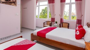 A bedroom with a bed, two chairs, a small table, and a window with curtains. - OYO 962 Tulip Motel (Da Nang)