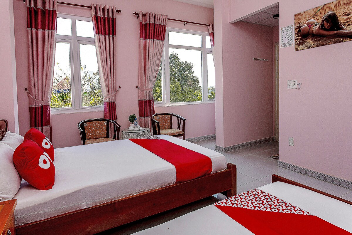 A room with a bed, a chair, a small table, and a window with curtains.