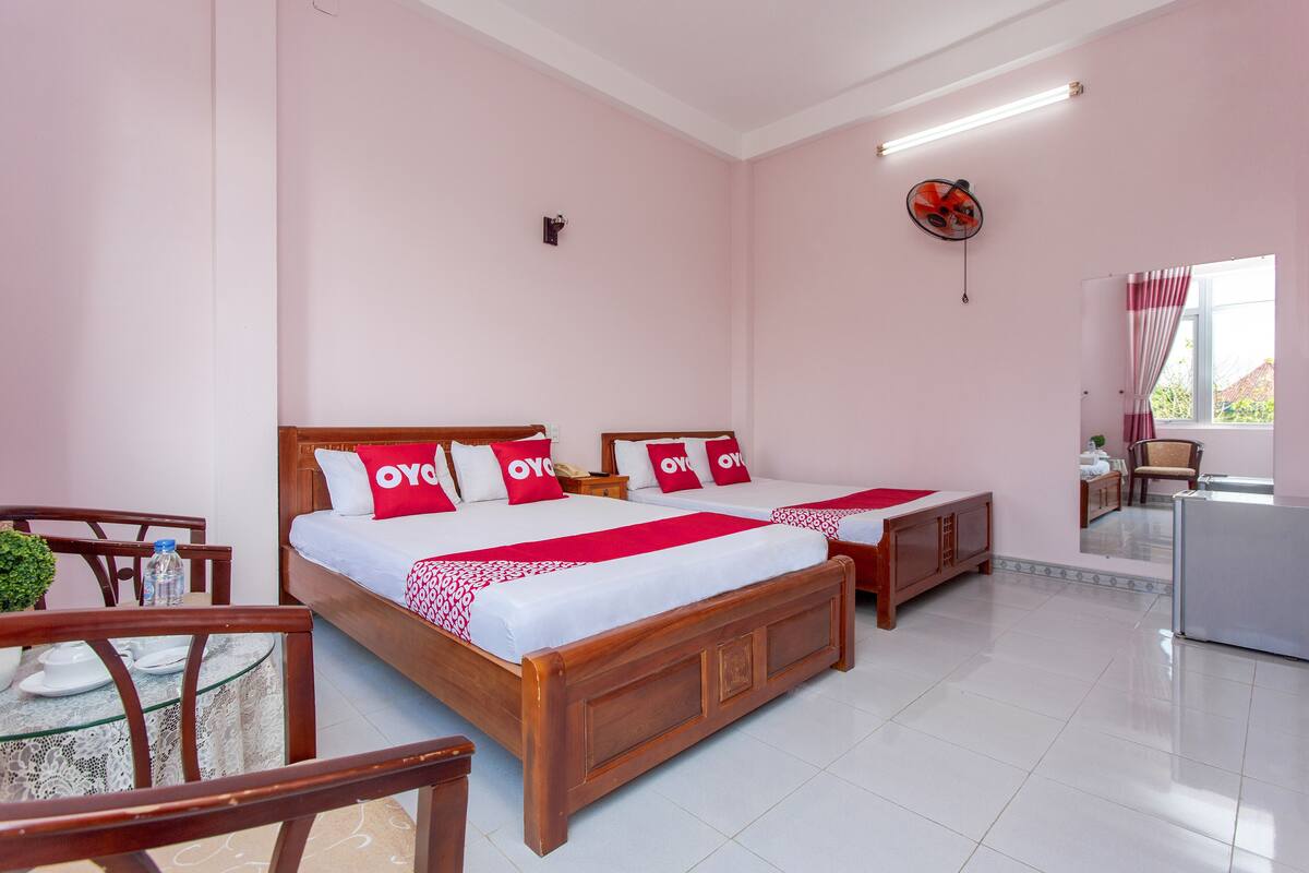 Habitación de hotel con dos camas, una mesita y un refrigerador.