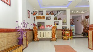 A reception area with a wooden bench, a reception desk, and a sign that reads "OYO". - OYO 962 Tulip Motel (Da Nang)